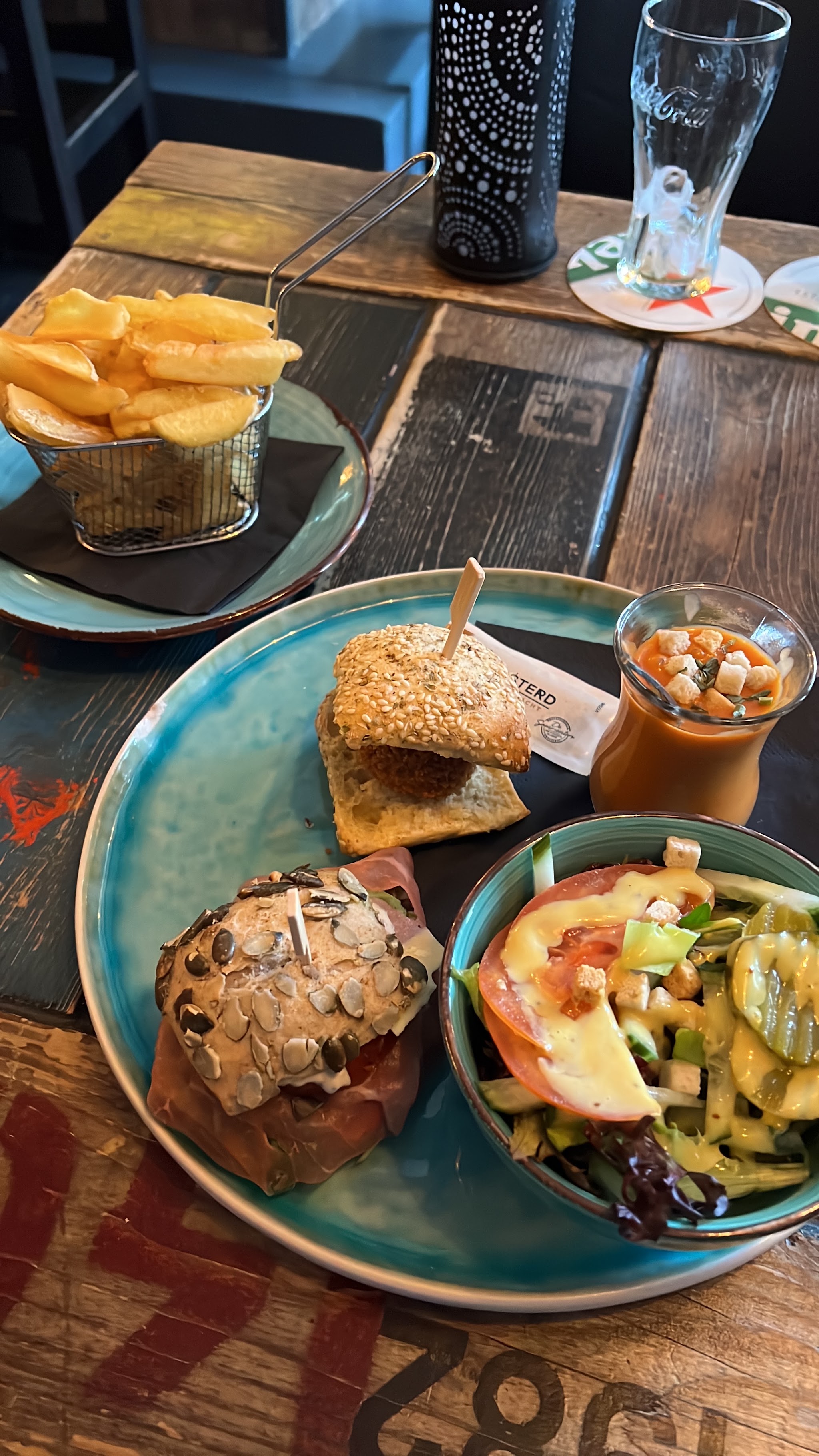 Een tafel met verschillende gerechten, frietjes en een drankje