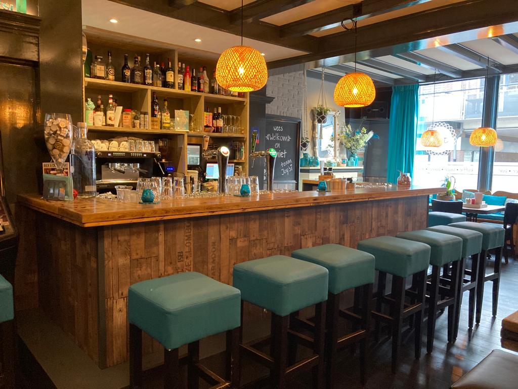 De houten bar met turquoise barkrukken en warme verlichting